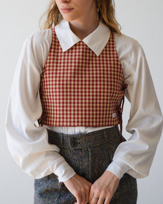 A woman is wearing a Red Check Australian handmade top in front of a white wall